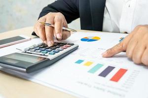 Asian accountant working and analyzing financial reports project accounting with chart graph and calculator in modern office, finance and business concept. photo