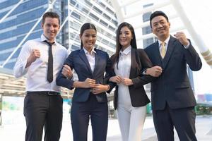 Cuatro ejecutivos seguidos, equipo empresarial de pie y vitoreando frente a la oficina moderna, concepto de liderazgo foto