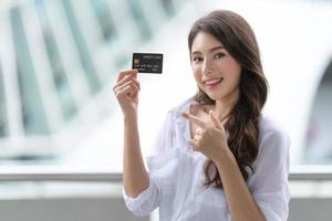 concepto de viernes negro, mujer con tarjeta de crédito y sonriendo cerca de la tienda