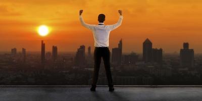 Businessman standing on roof and looking at Cityscape skyline photo