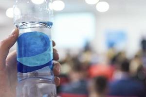 Business man on conference holding and drinking watter bottle. photo