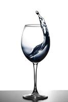 a splash of water in a glass wine glass. water splash in glass on glowing background. transparent liquid splashing in wine glass. Food, object. photo