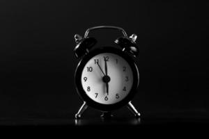 Black old style alarm clock isolated on black background. close-up photo