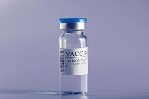ampolla con vacuna covid-19 en laboratorio. para luchar contra la pandemia del coronavirus sars-cov-2. primer plano médico del frasco de vidrio aislado en un fondo azul.