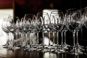 copas de vino vacías. Hermosas copas nuevas para vino de soporte de vidrio en filas pares sobre una mesa de madera en un restaurante. enfoque selectivo foto