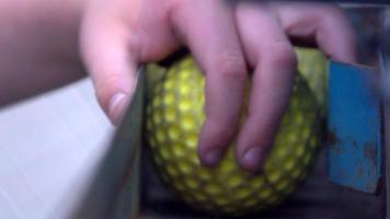 Detalles de una máquina de lanzamiento vintage cargada con pelotas de béisbol amarillas. video