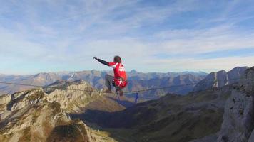 Vista aérea de un hombre en equilibrio mientras se relaja en la cuerda floja en las montañas.