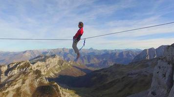 Vista aérea de un hombre en equilibrio mientras se relaja en la cuerda floja en las montañas.