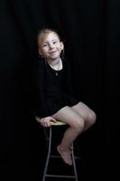 Little gymnast girl on a stool on a black background photo