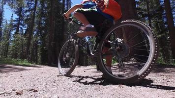 A boy rides his mountain bike on a singletrack dirt trail in the woods.