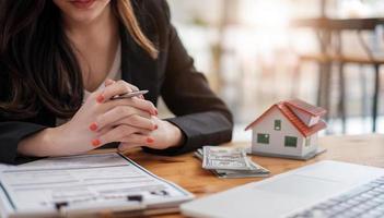 Agente de bienes raíces con modelo de casa firmando contrato a mano, tener un contrato vigente para protegerlo, firmar acuerdos modestos en la oficina. concepto de bienes raíces, mudarse de casa o alquilar propiedad foto