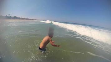 pov vista de un niño nadando en las olas en la playa. video