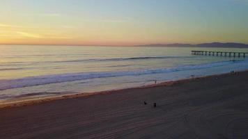 vista aerea drone uav di un molo al tramonto sulla spiaggia e sull'oceano. video