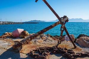 Rusty anchor on the shore at Aegina harbour in Greece photo