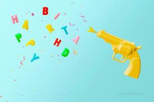 Pistola amarilla disparando velas de cumpleaños de colores y confeti de colores, sobre fondo azul. concepto de feliz cumpleaños con espacio de copia foto