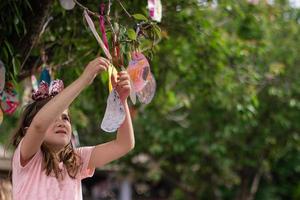 linda niña colgando del árbol sus tarjetas de pascua en forma de huevo, para buena suerte y con buenos deseos