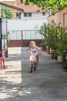 niña conduce su bicicleta en el patio trasero foto