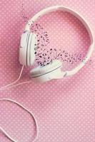 White headphones on pink background, with musical notes