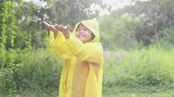 niño asiático jugando bajo la lluvia