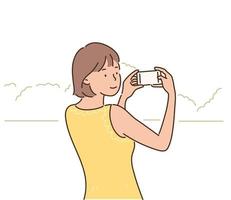 A woman is holding a camera and taking pictures of a landscape. hand drawn style vector design illustrations.