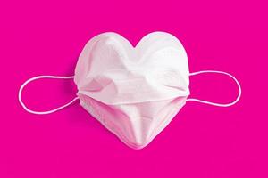 Surgical mask in the form of heart over colorful background photo