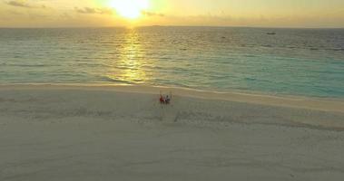 Vista aérea de un hombre y una mujer cenando y cenando en una playa de una isla tropical. video