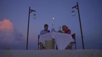 una pareja de hombre y mujer cenan y cenan en la playa de una isla tropical.
