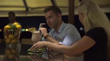 una pareja de hombre y mujer toman una copa en un bar en un resort. video