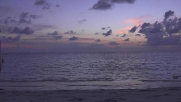 een paar wandelen op het strand bij zonsondergang in een resorthotel op een tropisch eiland.