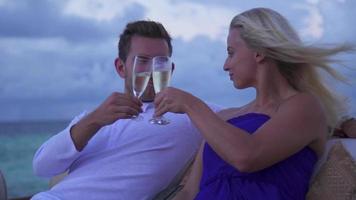 ett par skålar och dricker champagne på stranden på ett tropiskt öhotellhotell.