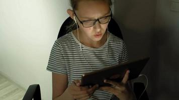 Jovencita usa tableta con auriculares por la noche