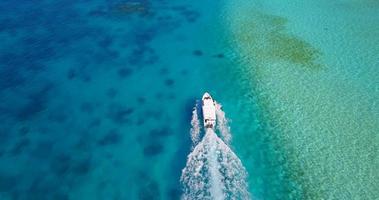 Vista aérea de un dron de una lancha a motor que va a una pintoresca isla tropical en las Maldivas. video