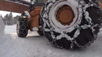 A snow plow tractor with snow chains for traction in the snow and ice.