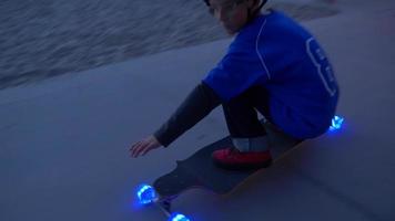 A boy rides a skateboard with led lights wheels in a neighborhood.