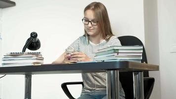 Una adolescente con gafas está sentada en un concepto de aprendizaje de pupitre escolar