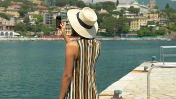 Una mujer con sombrero toma fotografías mientras viaja en una ciudad turística de lujo en Italia, Europa.
