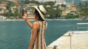 en kvinna i en hatt tar bilder när hon reser i en lyxig semesterort i Italien, Europa.