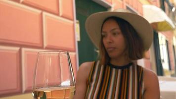 una donna beve vino quando viaggia in una località turistica di lusso in italia, europa. video