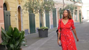 Una mujer caminando con un vestido rojo en una ciudad turística de lujo en Italia, Europa. video