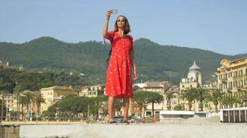 una donna si fa selfie mentre viaggia in una località turistica di lusso in italia, europa. video