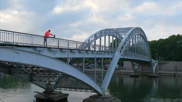 eine Frau streckt sich auf einer Bogenbrücke.