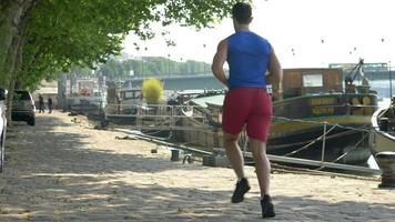 A couple running by boats on the river.