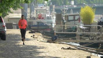 A woman running by boats on the river. video