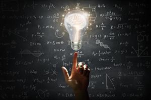 Hand holding a brain inside a light bulb on wall blackboard photo