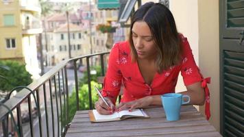 A woman writing in a journal diary traveling in a luxury resort town in Italy, Europe. video