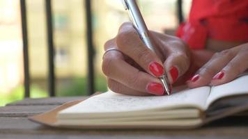 Close-up of a woman writing in a journal diary traveling in a luxury resort town in Italy, Europe. video