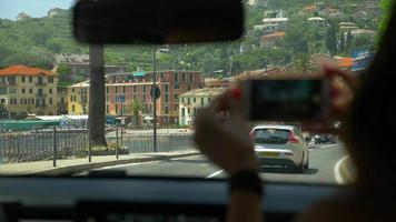 conduciendo pov de una mujer tomando fotos con un teléfono por la ventanilla del automóvil. video