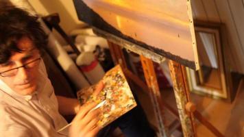 un artista dipinge un dipinto ad olio su tela all'interno del suo studio d'arte. video