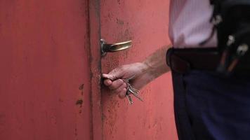 un uomo usa le sue chiavi per aprire il cancello di una porta. video
