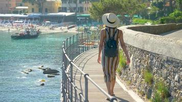 una mujer mira un club de playa del mar mediterráneo en una ciudad turística de lujo en italia, europa. video